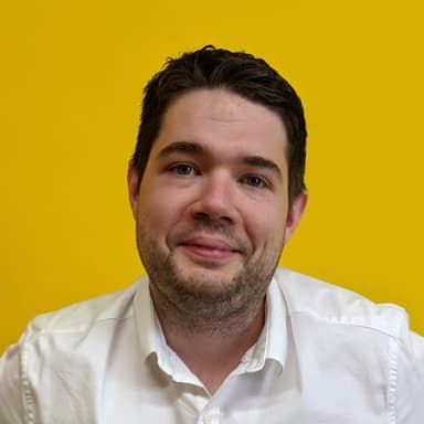 A photo of Kerri Sharp standing against a yellow backdrop
